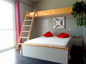 a bunk bed with two red pillows and a ladder at Pousada B&B Le Gourmet in São Pedro