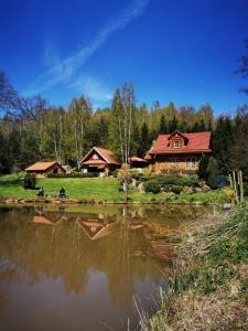 a log cabin next to a pond with a house at Chata Zbychówka in Prezezdziedza