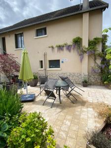 eine Terrasse mit einem Tisch, Stühlen und einem Sonnenschirm in der Unterkunft l'ANNEXE in Verdigny