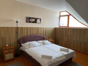1 dormitorio con 1 cama con sábanas blancas y ventana en Muskátli Panzió és Étterem, en Újhartyán