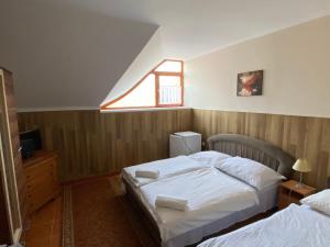 1 dormitorio con 2 camas y ventana en Muskátli Panzió és Étterem, en Újhartyán