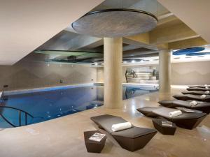 a large swimming pool with chairs and a large ceiling at Swissôtel Resort Bodrum Beach in Turgutreis