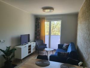 Una sala de estar con un sofá azul y un televisor. en Apartament Słoneczny 28 Słoneczna Dolina, en Jastrzębia Góra