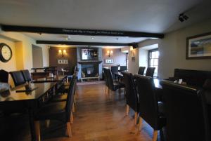 a dining room with tables and chairs and a fireplace at the punchbowl hotel in Kendal