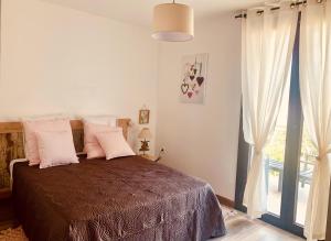 een slaapkamer met een bed met roze kussens en een raam bij APPARTEMENT LES COLLINES in Calvi
