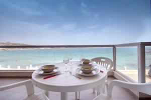 einen weißen Tisch und Stühle mit Meerblick in der Unterkunft Enjoy Sunsets at Luxury 3BR APT in Mellieha Bay in Mellieħa
