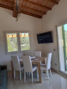 a dining room with a wooden table and white chairs at VILLETTA SANTA LUCIA in Marina di Campo