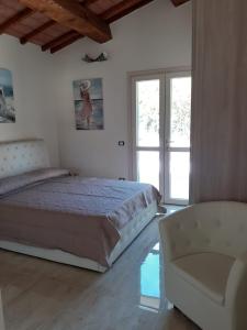 um quarto com uma cama grande e uma cadeira em VILLETTA SANTA LUCIA em Marina di Campo
