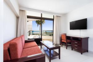 sala de estar con sofá, mesa y TV en Meliá Fuerteventura, en Costa Calma
