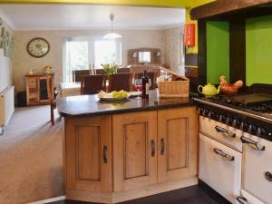 een keuken met groene muren en een eiland met een fornuis bij Carreg Y Garth Isaf - Hot Tub Nr Zip World in Bangor
