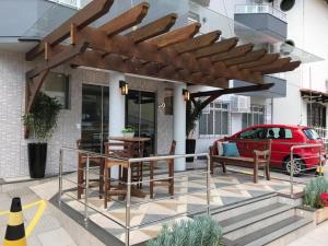a patio with a wooden pergola and a red car at Hotel Contessi in Urussanga