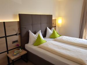 a hotel room with a bed with green pillows at Pension Gartscheid in Lana