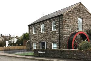 un bâtiment en briques avec une grande roue sur son côté dans l'établissement Stone Flax Mill, à Connor