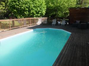 a swimming pool with two chairs and a wooden deck at La Maison d'hôtes du Chapelier in Espéraza