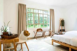 um quarto com uma cama, uma secretária e uma janela em The Safari House em Usa River