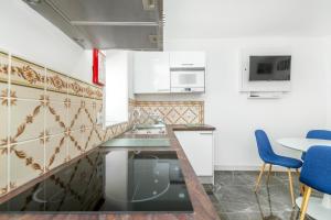 a kitchen with white cabinets and blue chairs at Maredimo Village Casa 6 in Porto