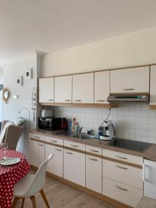 uma cozinha com armários brancos, uma mesa e uma sala de jantar em Santiago seaview em Oostende