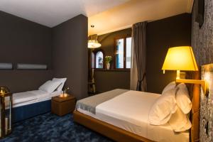 a hotel room with two beds and a lamp at Riva del Vin BOUTIQUE HOTEL in Venice