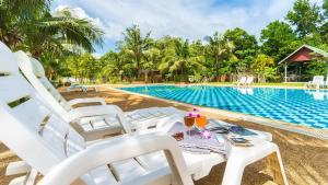 a pool at the resort with white chairs and a table at Doo Dee Boutique Resort by Swiss Chalet in Ao Nang Beach