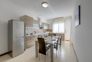 Il comprend une cuisine équipée d'une table, de chaises et d'un réfrigérateur. dans l'établissement Modern 3 Bedroom Apartment in Central Sliema, à Sliema