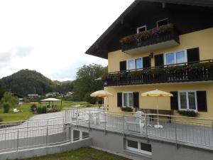 ein Gebäude mit einem Balkon mit Blumen und einem Sonnenschirm in der Unterkunft Haus Amalia in Strobl