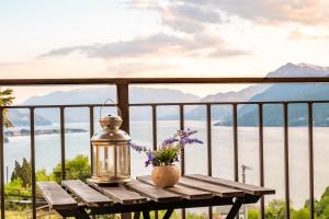 einen Tisch mit einer Laterne und Blumen auf dem Balkon in der Unterkunft B&B e Residence Abbazia di Piona in Colico