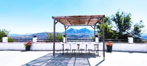 a table and chairs under acoveredilion with a view of mountains at Molino El Vinculo in Zahara de la Sierra