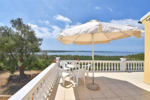 a patio with a table and an umbrella on a balcony at Villa Menethea Sea View - 5min from Issos beach in Línia