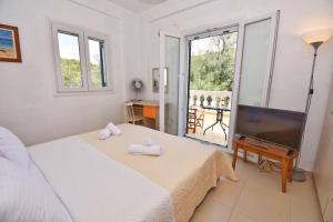 a white bedroom with a bed and a television at Villa Menethea Sea View - 5min from Issos beach in Línia