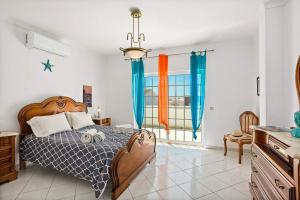 a bedroom with a large bed with blue curtains at Villa Hope by Villa Plus in Galé
