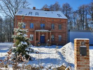 una casa de ladrillo rojo en la nieve con un árbol de Navidad en Uroczysko Gryżyna, en Gryżyna