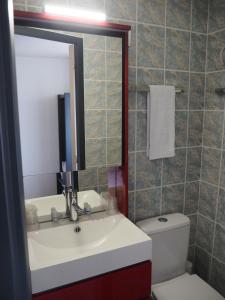 W łazience znajduje się umywalka, toaleta i lustro. w obiekcie HOTEL LE FOIRAIL w mieście Figeac