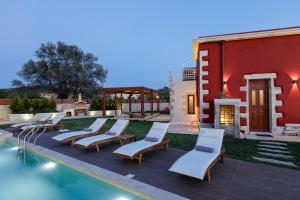 a group of lounge chairs next to a swimming pool at Villa Rossa in Arkhondikí