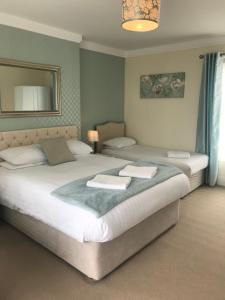 a bedroom with two beds and a mirror at Rooms at The Highcliffe in Aberporth