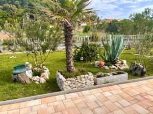 un jardín con una palmera y algunas rocas en Casa Fumica Studio, en Kampor