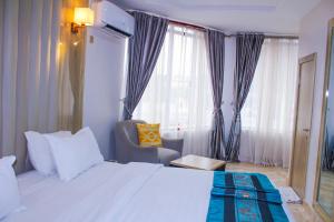 a bedroom with a bed and a chair and a window at Hilton Leisure Resort in Akwa