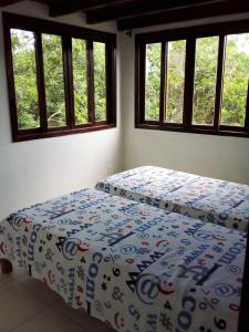 1 dormitorio con 1 cama con edredón y ventanas en F2xs Guest house en Saquarema