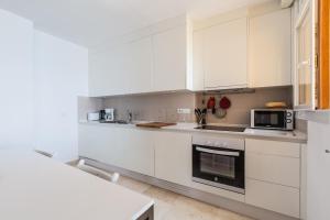 a white kitchen with white cabinets and a microwave at Los Reales 8B in Estepona +20 photos