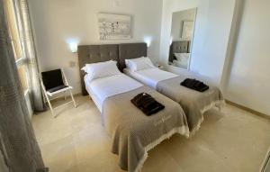 two beds in a room with a mirror and a chair at Los Reales 8B in Estepona