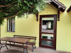 a wooden bench next to a yellow building with a door at Pensjonat Cichy Kącik in Kąty Rybackie