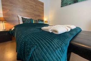 a bedroom with a green bed with towels on it at Esprit Luxe .... au coeur de Mulhouse in Mulhouse
