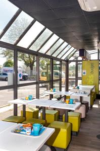 a restaurant with white tables and yellow chairs at ibis budget Antony Massy rénové 2024 in Antony