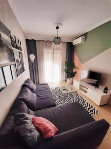 uma sala de estar com um sofá e uma televisão de ecrã plano em Sweet Apartment em Tessalônica