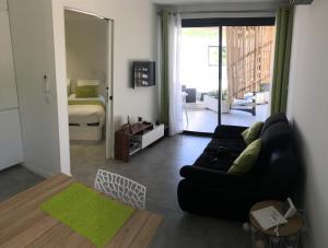 a living room with a black couch and a bedroom at Cassis Lodges in Cassis