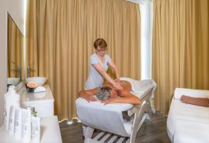 Una donna che fa un massaggio a un uomo in un salone di bellezza di Hotel Narcis - Maslinica Hotels & Resorts a Rabac