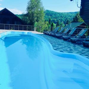 a large swimming pool with a row of empty chairs at Gostynnyi Dvir VIP HOUSE in Migovo