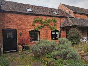 a brick house with a black door and windows at Lupin Cottage at Boningale Manor in Wolverhampton