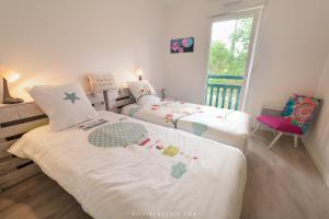 2 camas individuales en una habitación con ventana en Natsuocean, en Vieux-Boucau-les-Bains