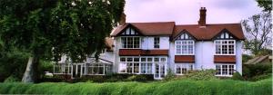 una grande casa bianca con il tetto marrone di Lupin Cottage at Boningale Manor a Wolverhampton