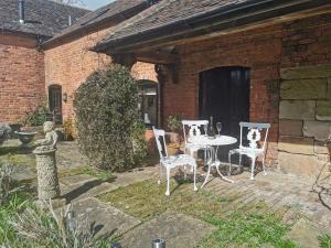 un patio con tavolo e sedie in un cortile di Lupin Cottage at Boningale Manor a Wolverhampton Altre 2 foto